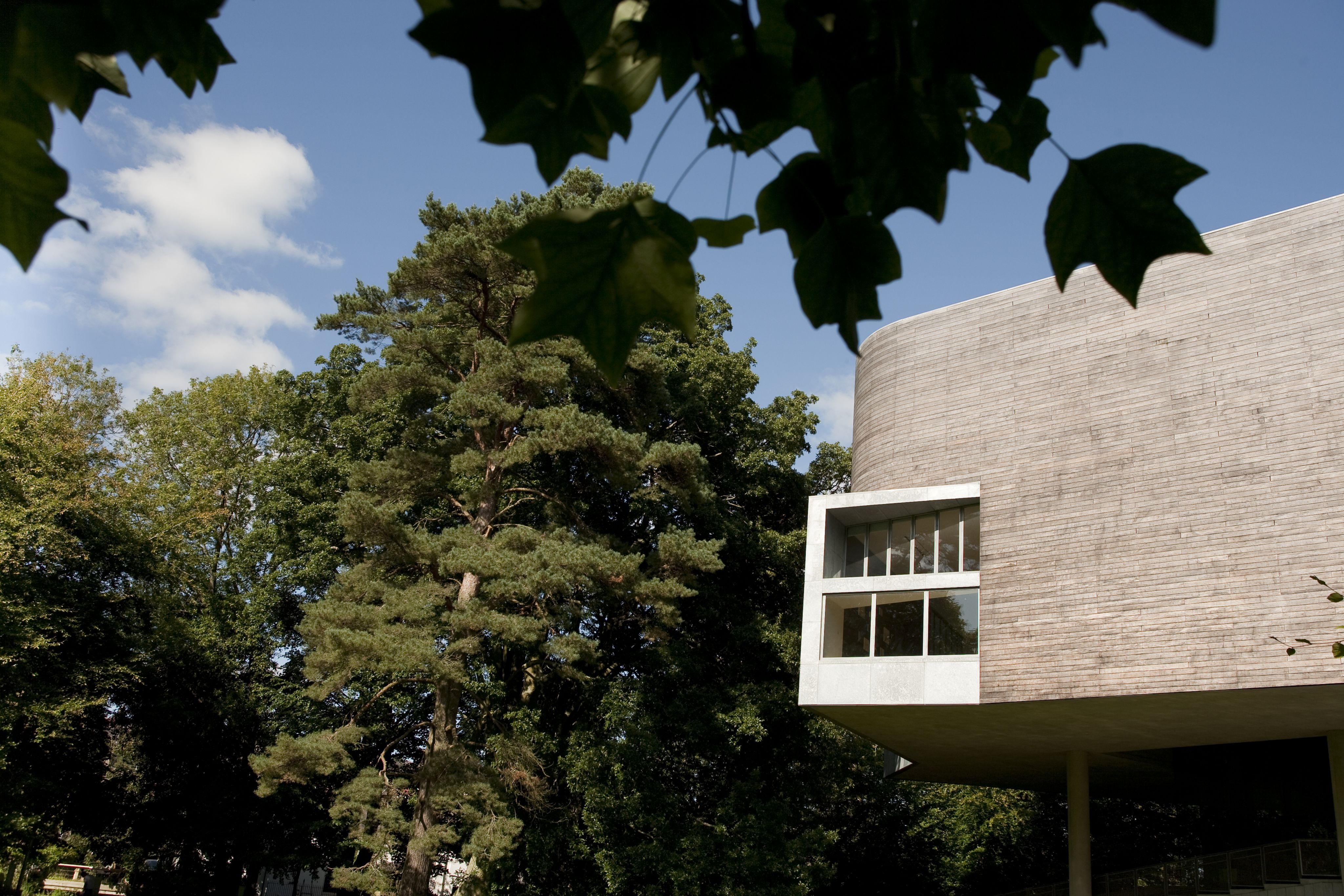 Picture of Glucksman Gallery through leaves with a blue sky and cloud showing